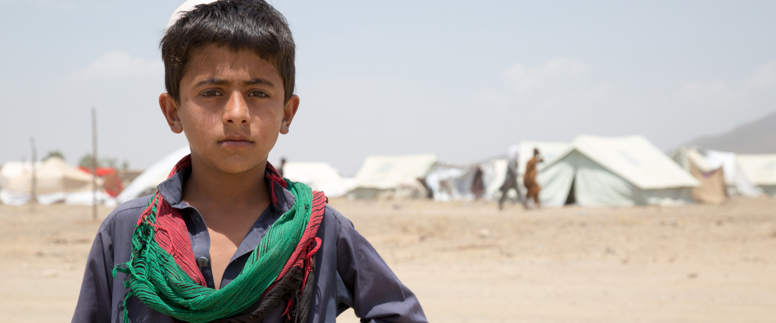 Jongen in Afghaans vluchtelingenkamp. | Foto: Matthew Graydon | IOM, 2014 Jongen in Afghaans vluchtelingenkamp. | Foto: Matthew Graydon | IOM, 2014