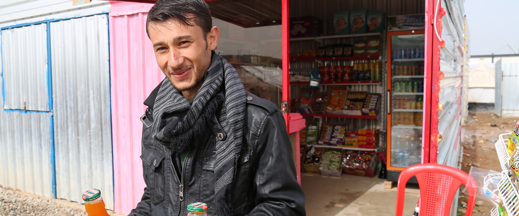 Syrische vluchteling voor zijn winkel in het Gawer Gosik-kamp, Turkije. | Foto: Taryn Fivek | IOM 2015