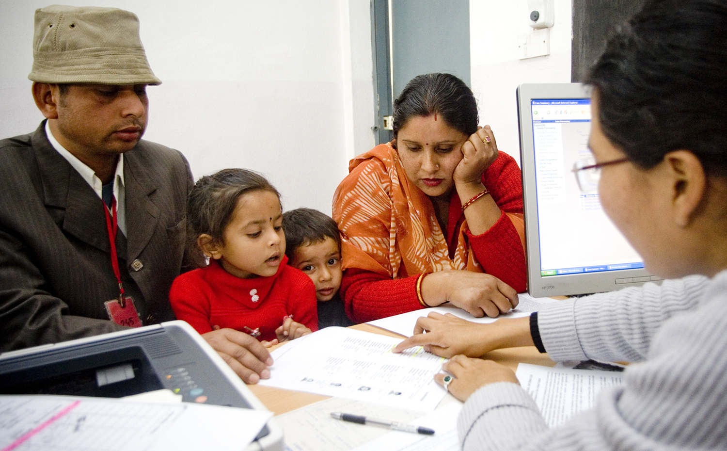 Immigratiemedewerker begeleidt Indiaas gezin. Foto: IOM 2013