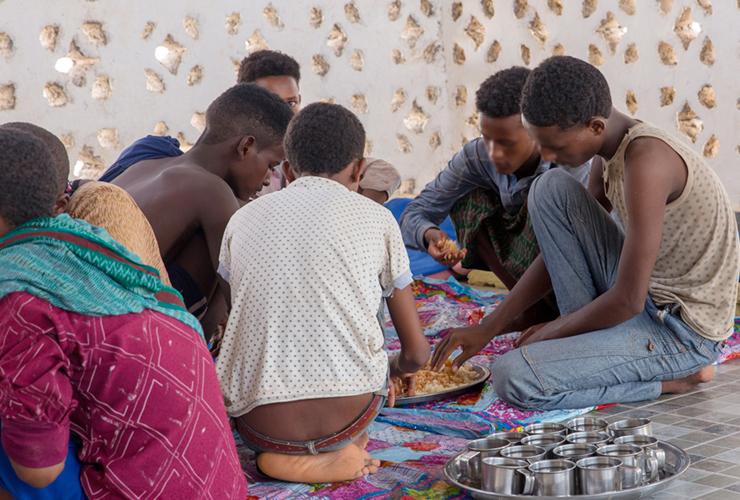 Alleenstaande Somalische jonge migranten eten samen een maaltijd in het Migration Response Center van IOM, waar ze worden verzorgd terwijl ze wachten op hun terugkeer naar huis. IOM voert het traceren van familieleden uit voor niet-begeleide kinderen. Foto: IOM 2018