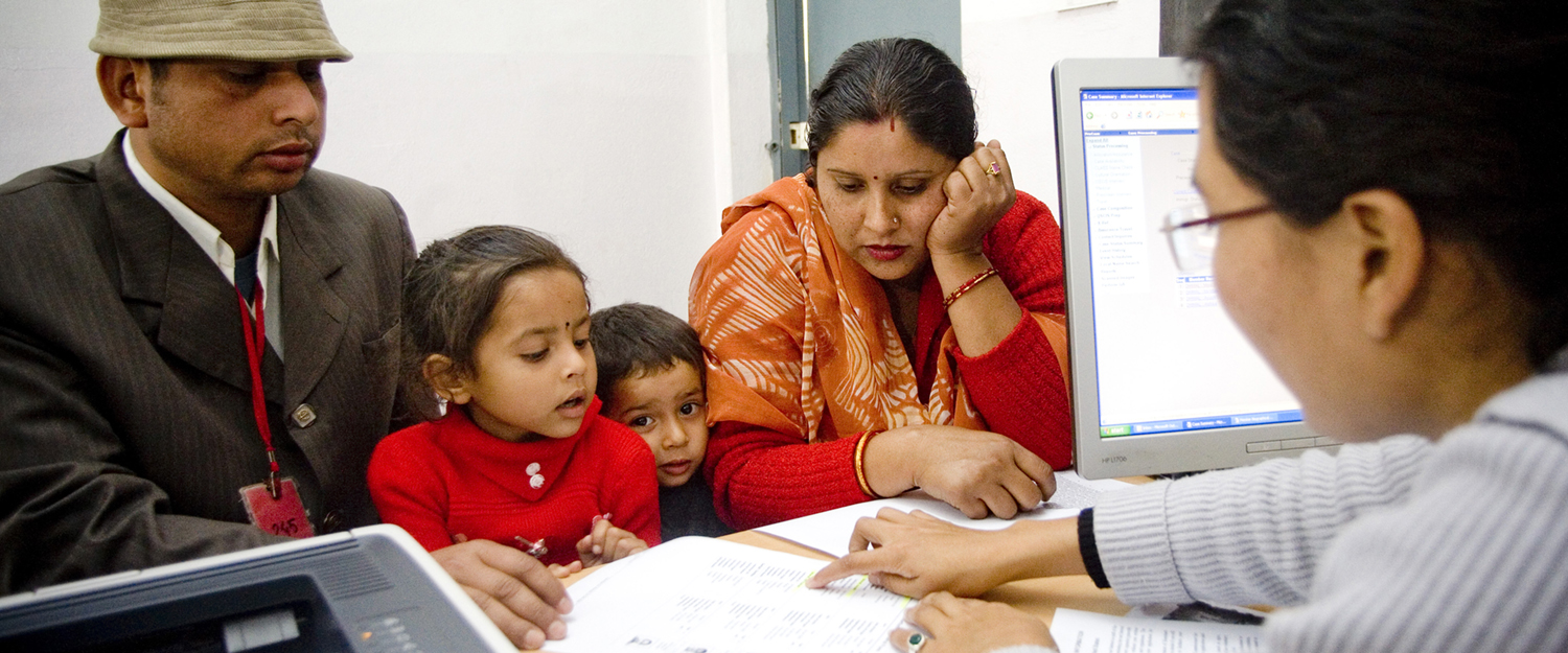Immigratiemedewerker begeleidt Indiaas gezin. | Foto: IOM 2013