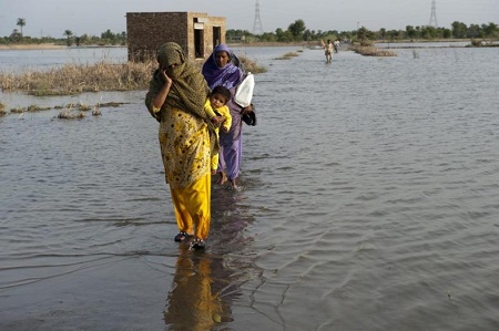 Mensen waden door een overstroomde rivier, India