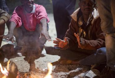 Illegale bewoners rond het kampvuur in een kamp bij Calais. | Foto: Amanda Nero | IOM, 2015